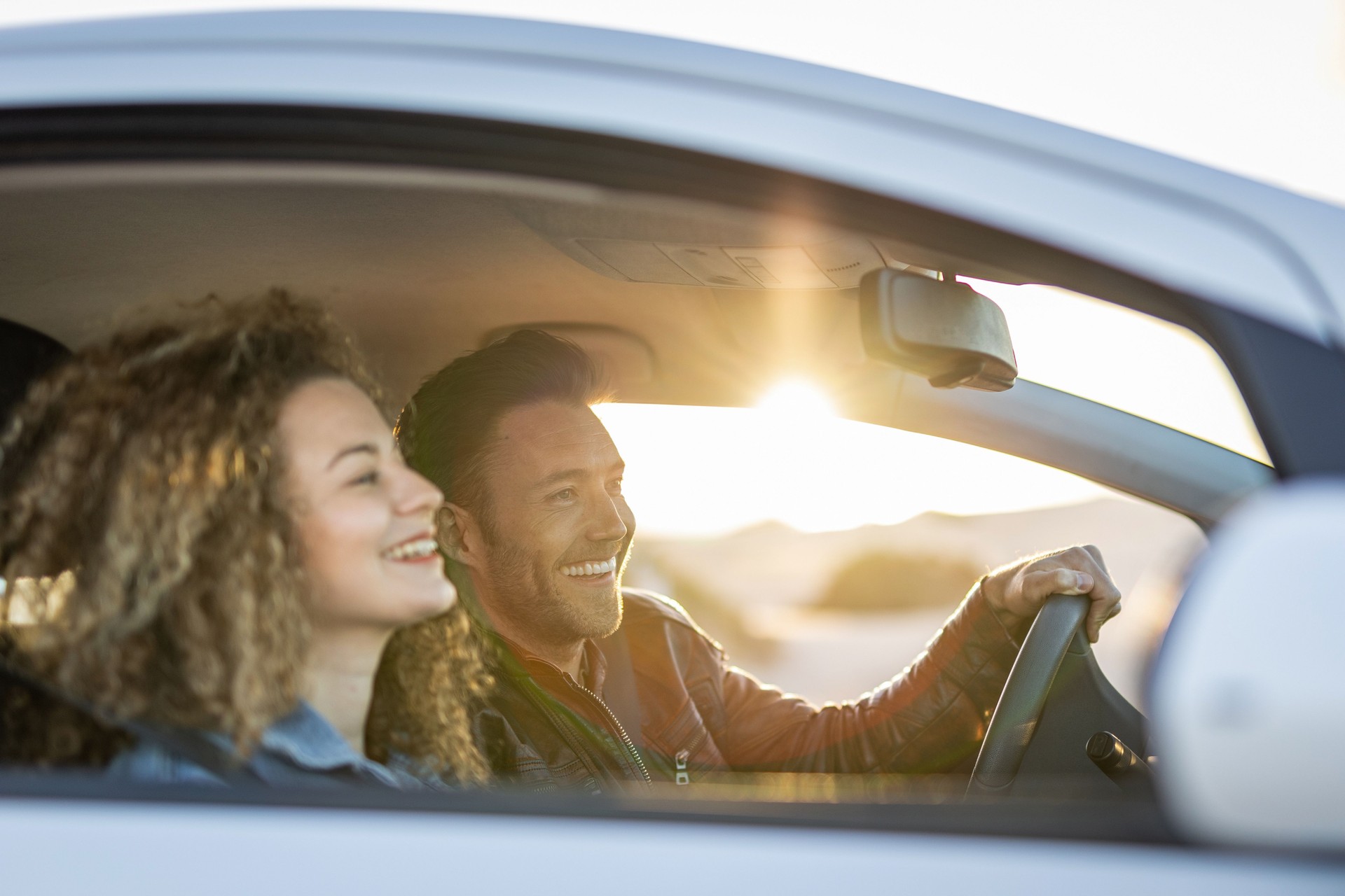 Happy young couple enjoying a car ride, traveling on vacation.